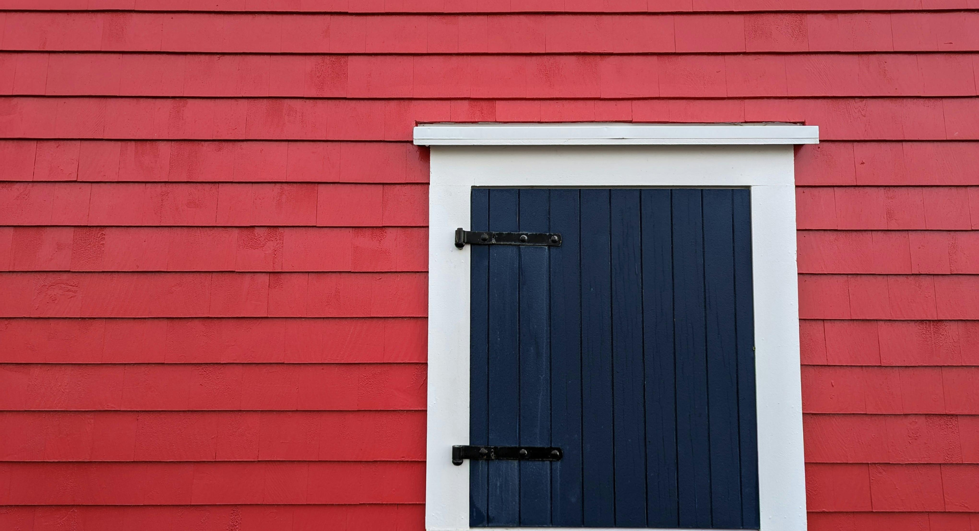 Un bâtiment rouge avec une porte bleue et des garnitures blanches