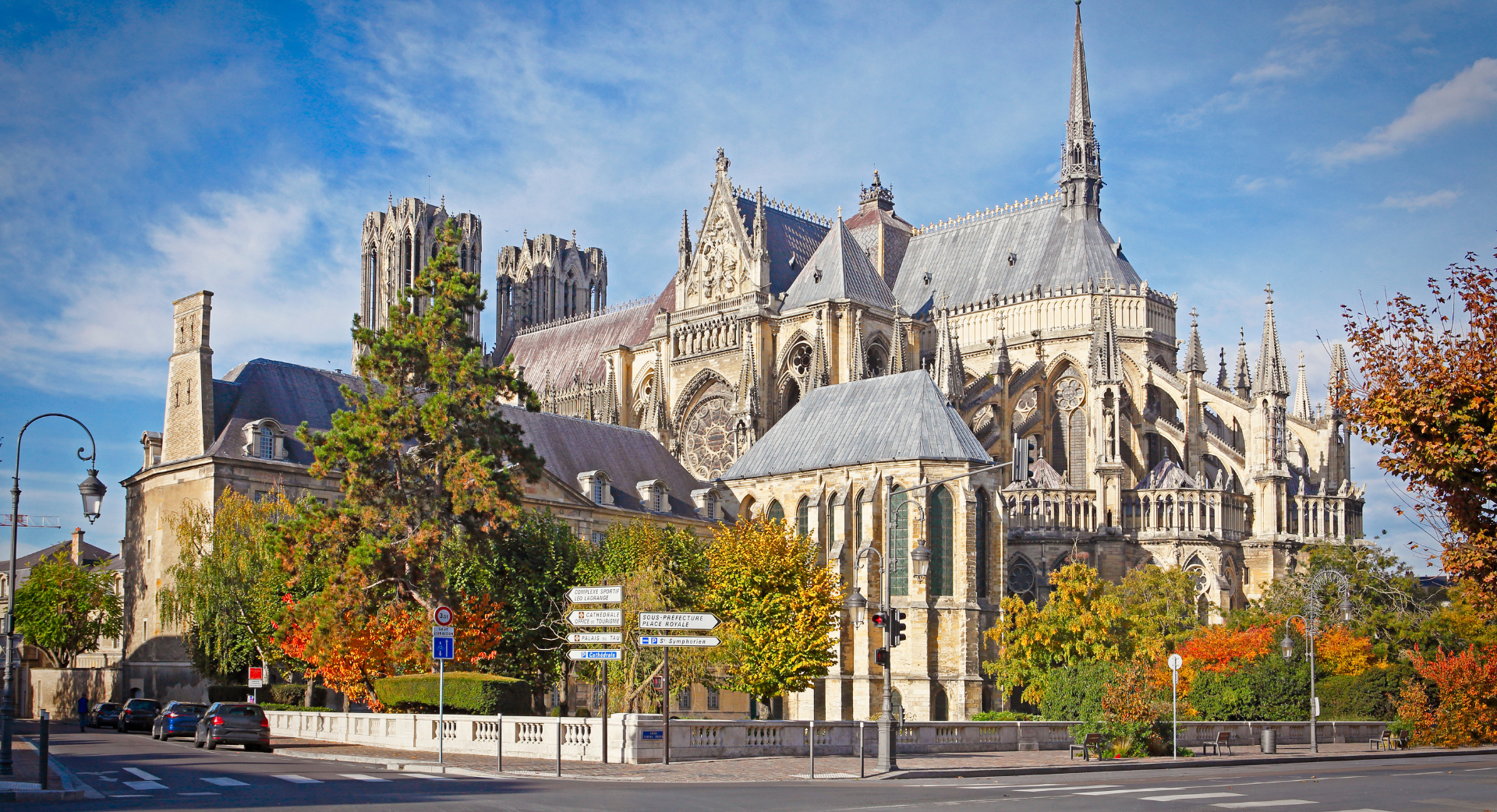 Une grande cathédrale est entourée d'arbres et d'une rue.