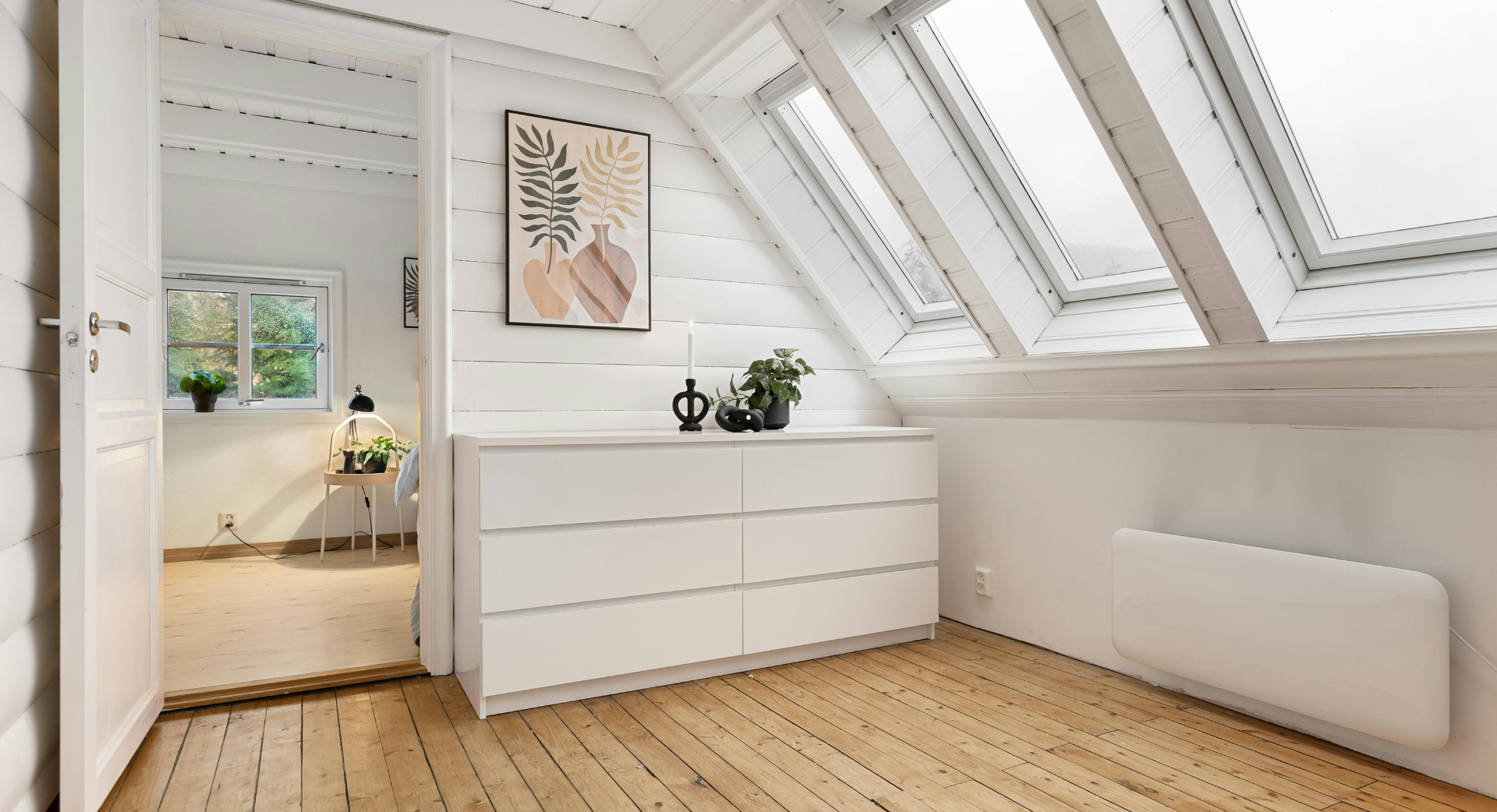 Une chambre avec une commode et un tableau au mur.