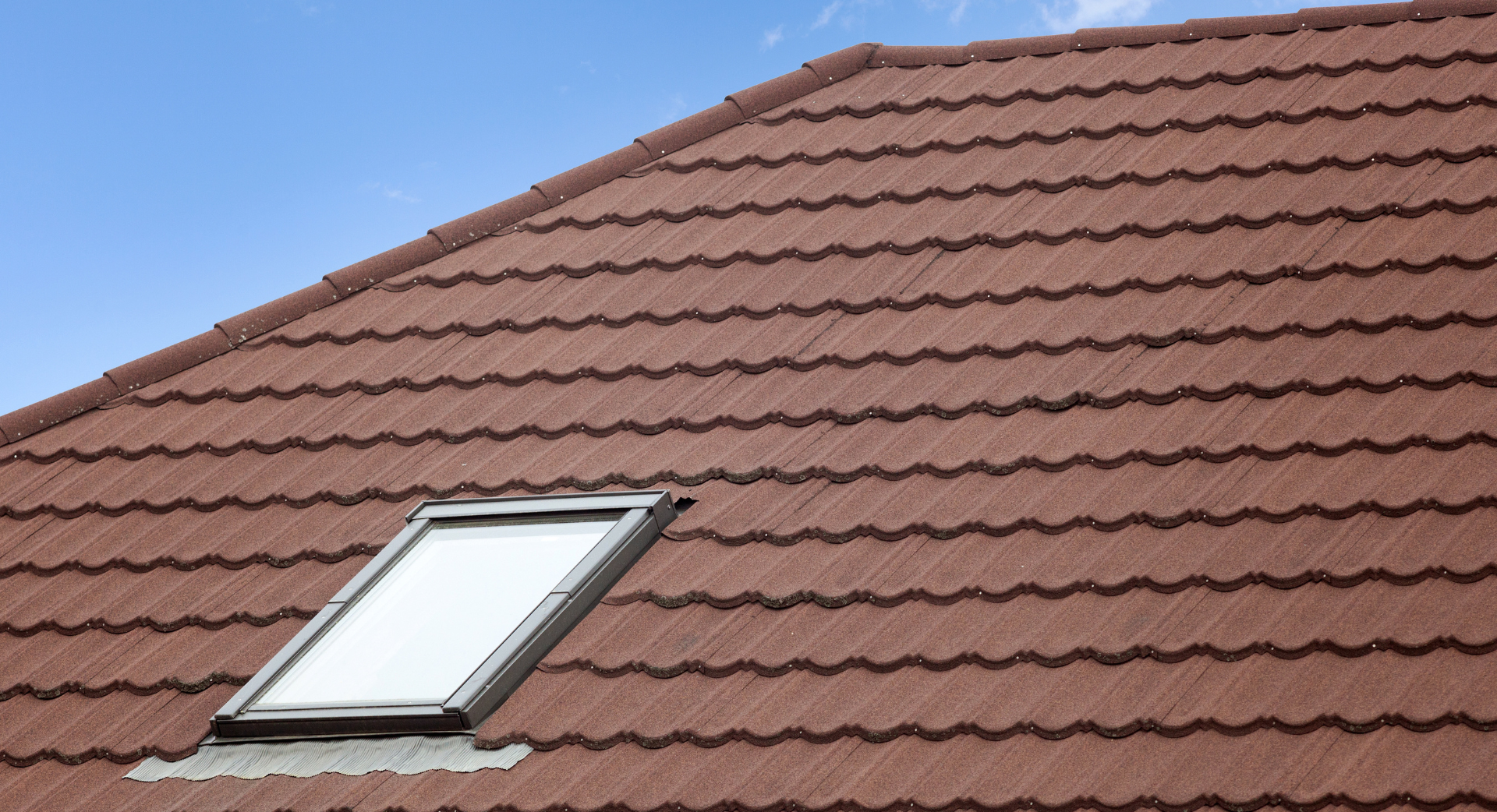 Un toit avec une lucarne et un ciel bleu en arrière-plan.