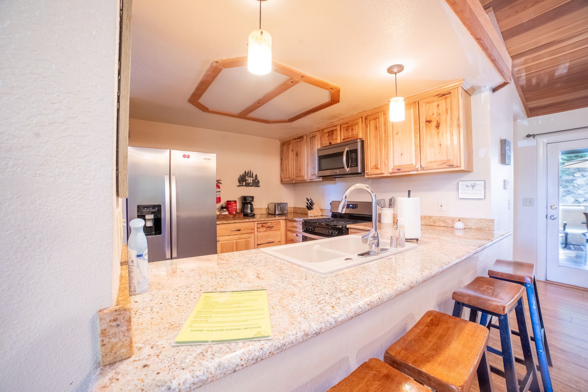 Kitchen with light wood cabinets, a breakfast bar, and stainless steel appliances.