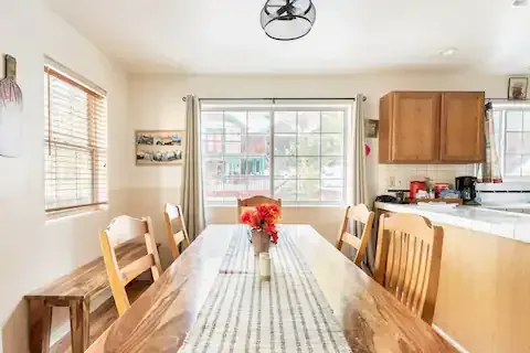 Dining room with wooden table, bench, and chairs, overlooking a window with a view.