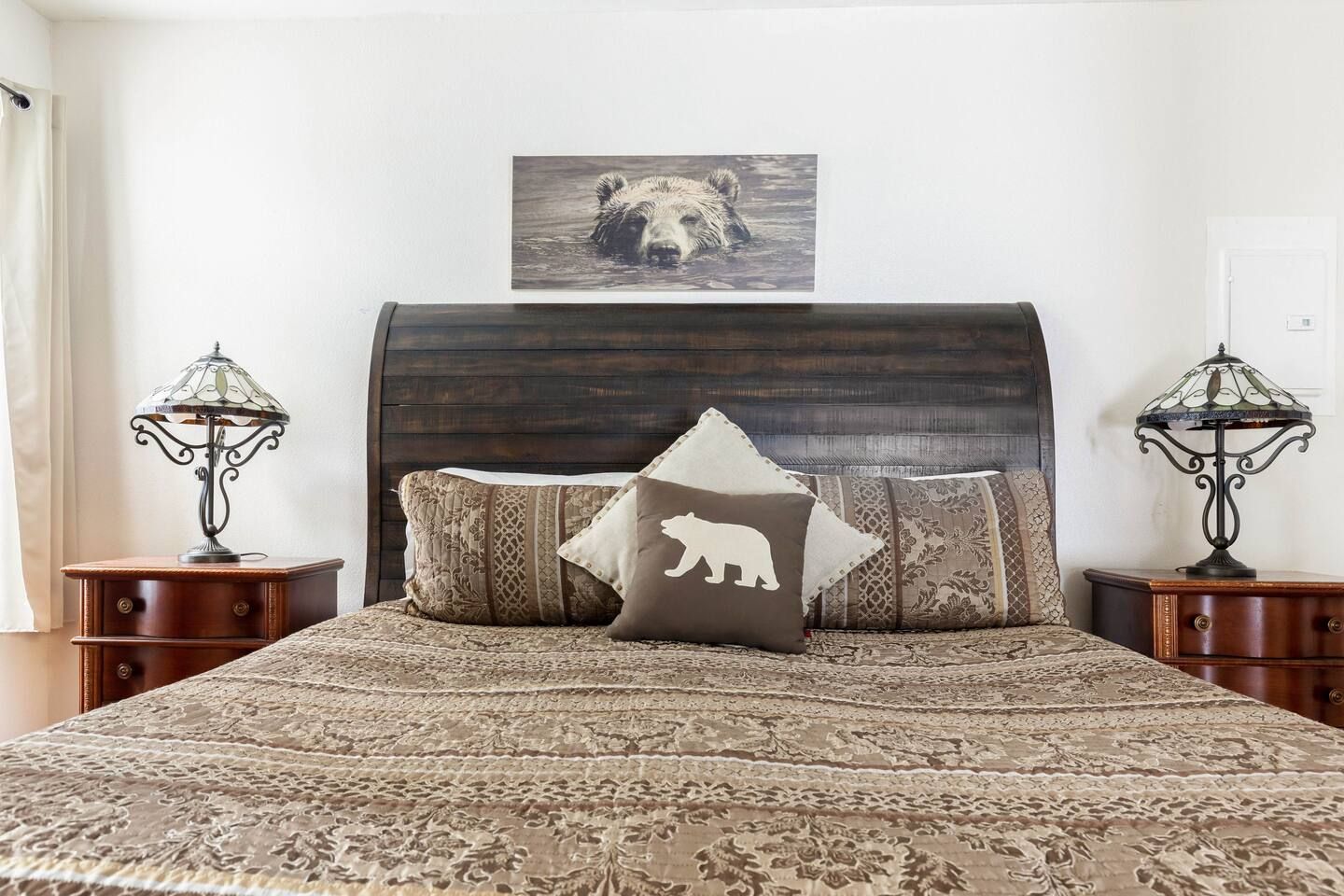 Bedroom with a wooden headboard, nightstands, and a bed with pillows and a bear-themed throw.