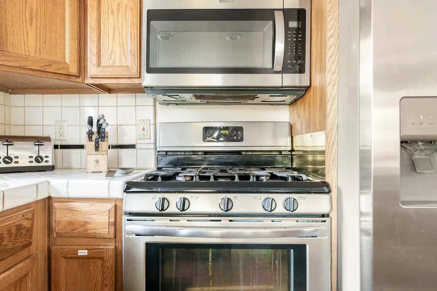 Stainless steel oven, microwave, and refrigerator in a kitchen with wooden cabinets.