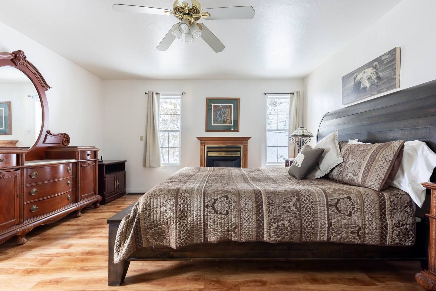 Bedroom with wooden furniture, a fireplace, and a patterned bedspread.
