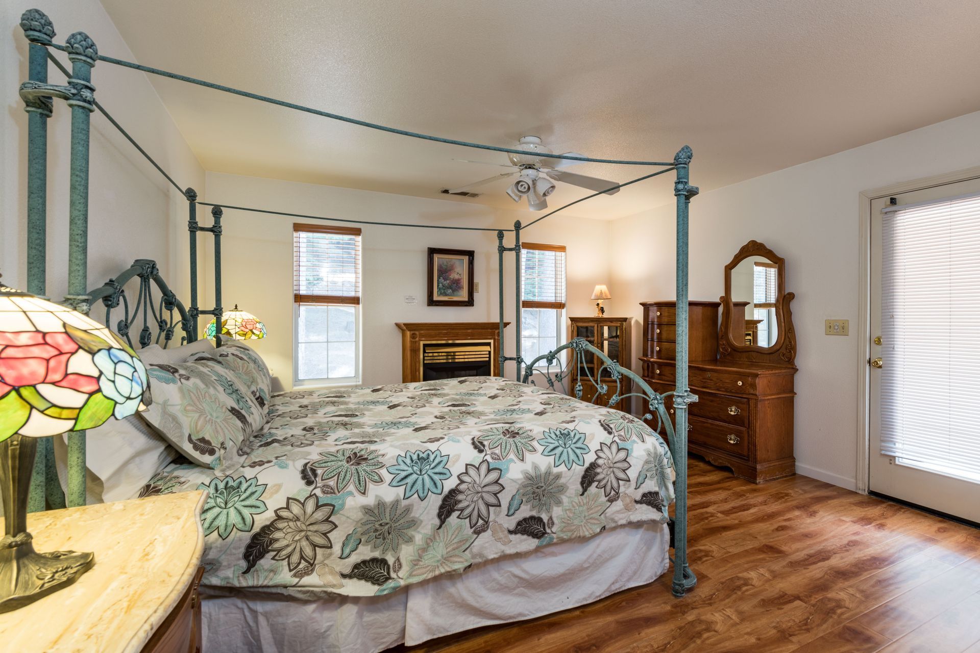 Bedroom with canopy bed, fireplace, wooden furniture, and a door to the outdoors.