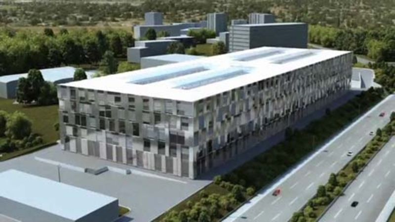 Une vue aérienne d'un grand bâtiment entouré d'arbres et d'une autoroute.