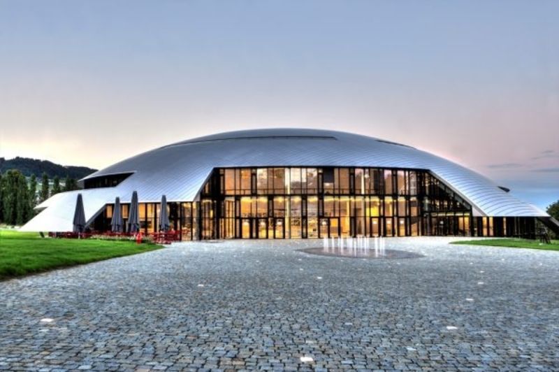 Un grand bâtiment en forme de dôme avec de nombreuses fenêtres se trouve au sommet d'un champ verdoyant.