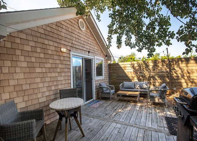 A wooden deck with a table and chairs in front of a house.