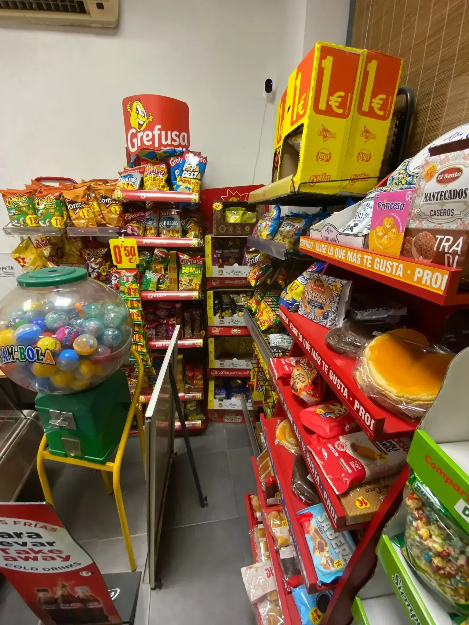 Un estrecho pasillo de dulces en una tienda de conveniencia, repleto de coloridos bocadillos y bolsas de papas fritas.