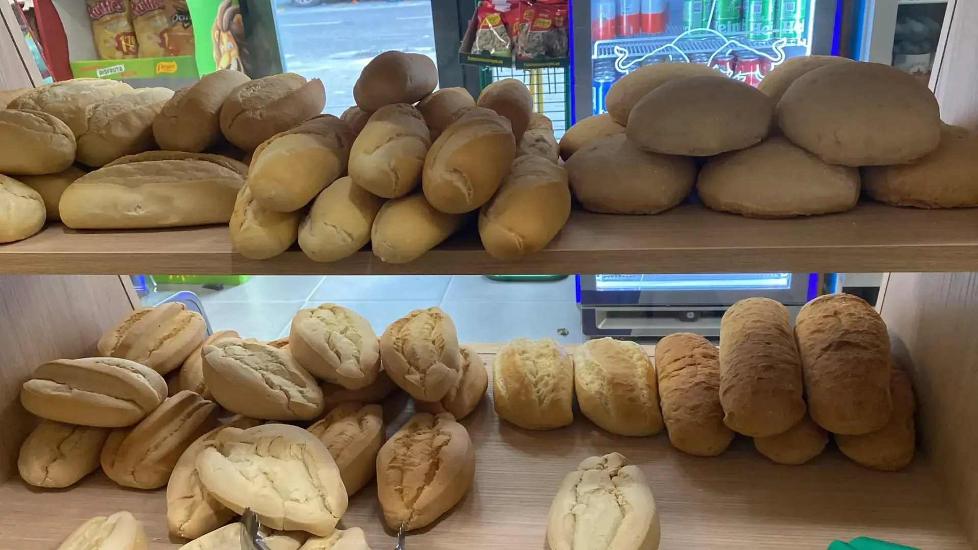 Estantes con panes y bollos surtidos en el mostrador de una panadería.