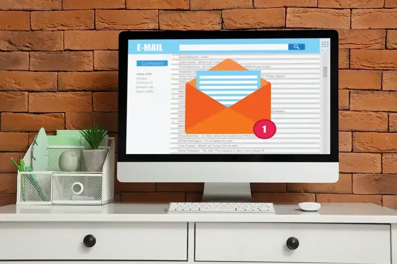 Una computadora está sobre un escritorio con un sobre en la pantalla.
