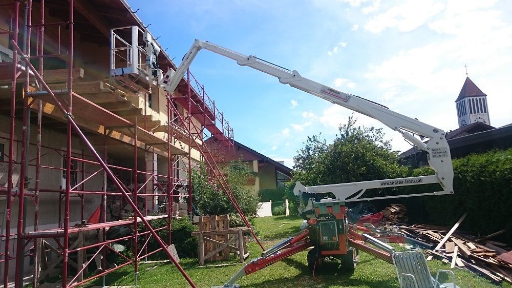 Mit einem Kran wird die Seite eines Gebäudes gestrichen.