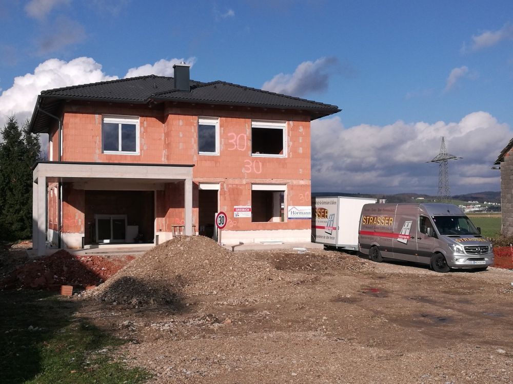 Ein im Bau befindliches Backsteinhaus mit einem davor geparkten Lieferwagen