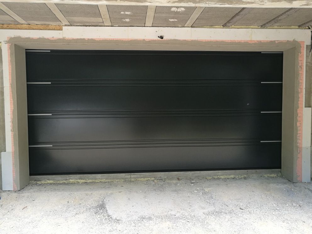 In einer im Bau befindlichen Garage steht ein schwarzes Garagentor.