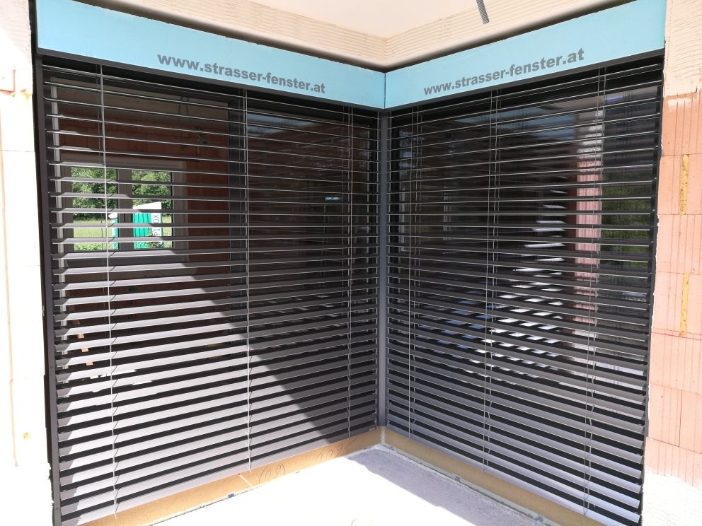 Eine Ecke eines Gebäudes mit Jalousien an den Fenstern