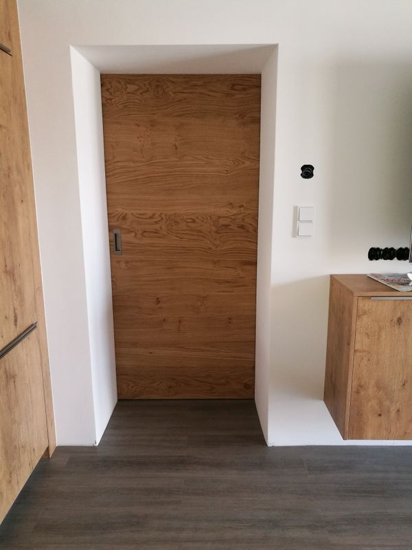 In der Mitte eines Raumes ist eine Holztür.