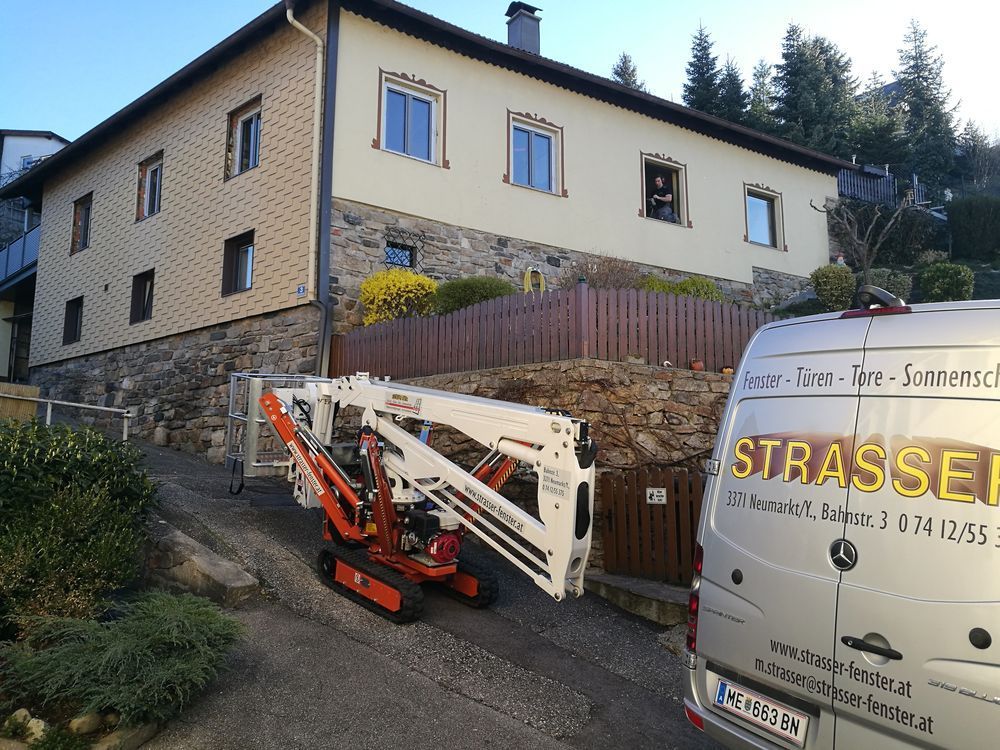 Ein weißer Lieferwagen mit dem Wort Strassel auf der Rückseite steht vor einem Gebäude