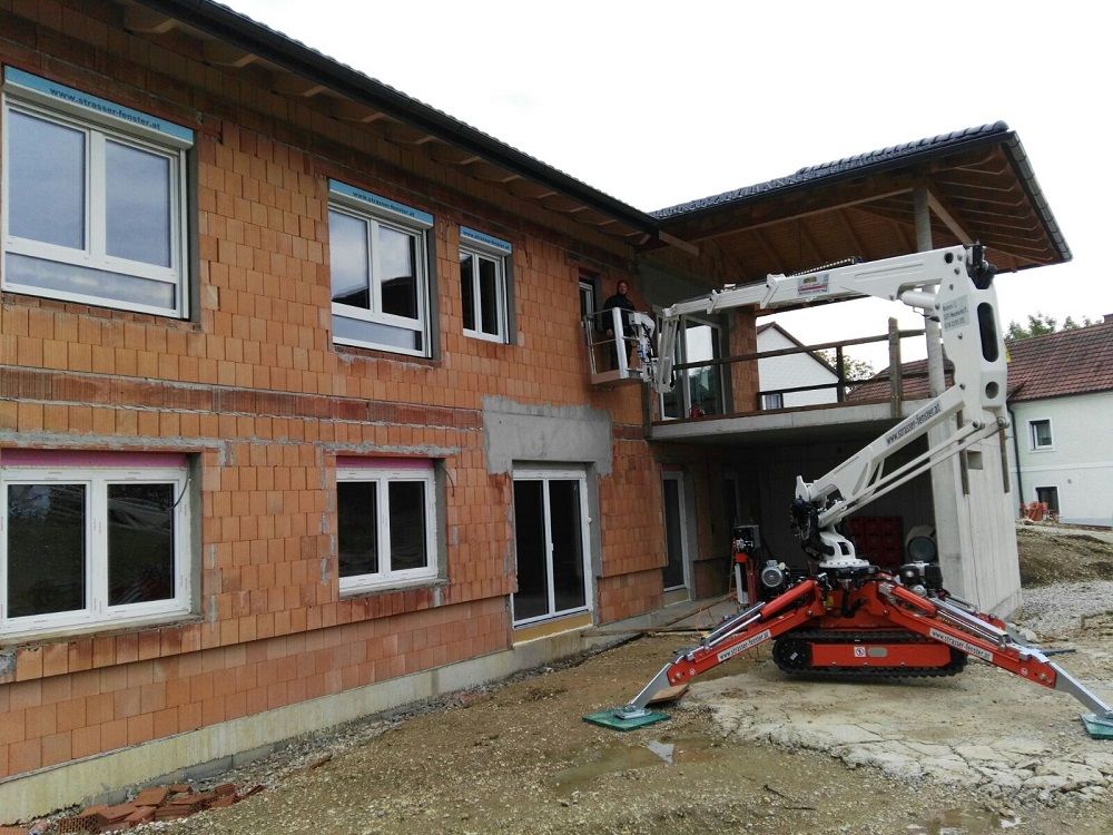 Ein Kran steht vor einem im Bau befindlichen Backsteingebäude.