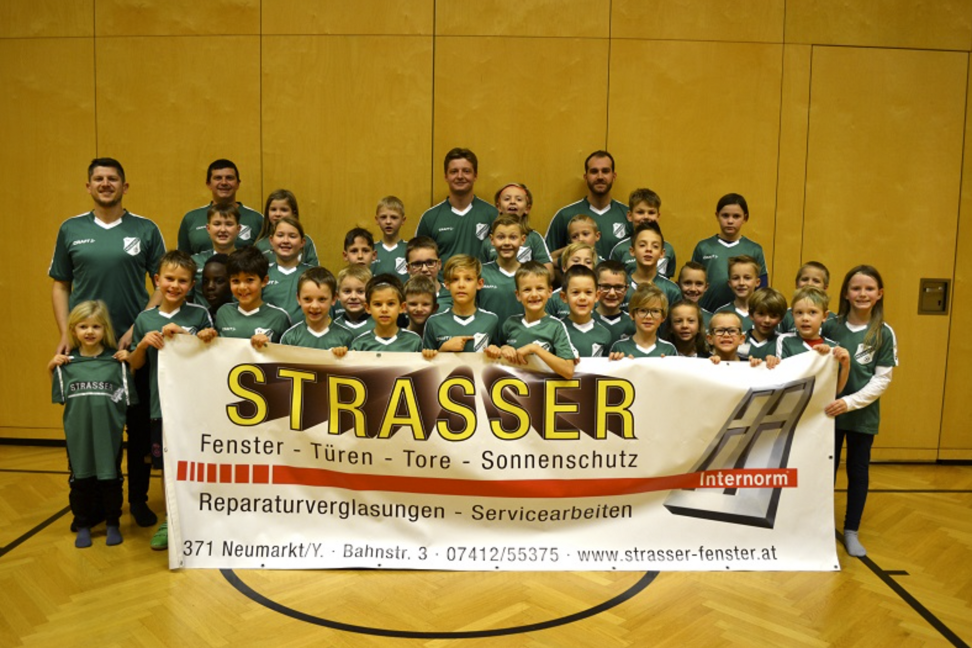 Eine Gruppe von Kindern, die ein Banner mit der Aufschrift „Strasser“ halten