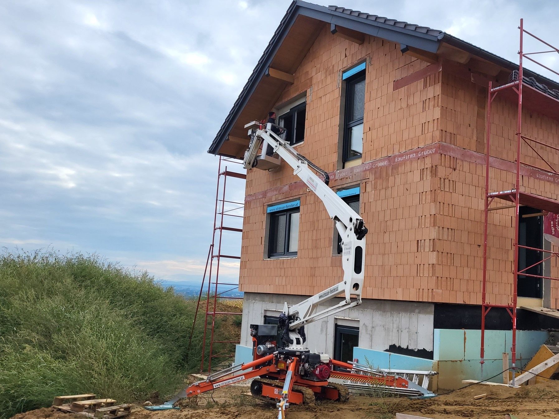 Ein Kran steht vor einem im Bau befindlichen Backsteingebäude.