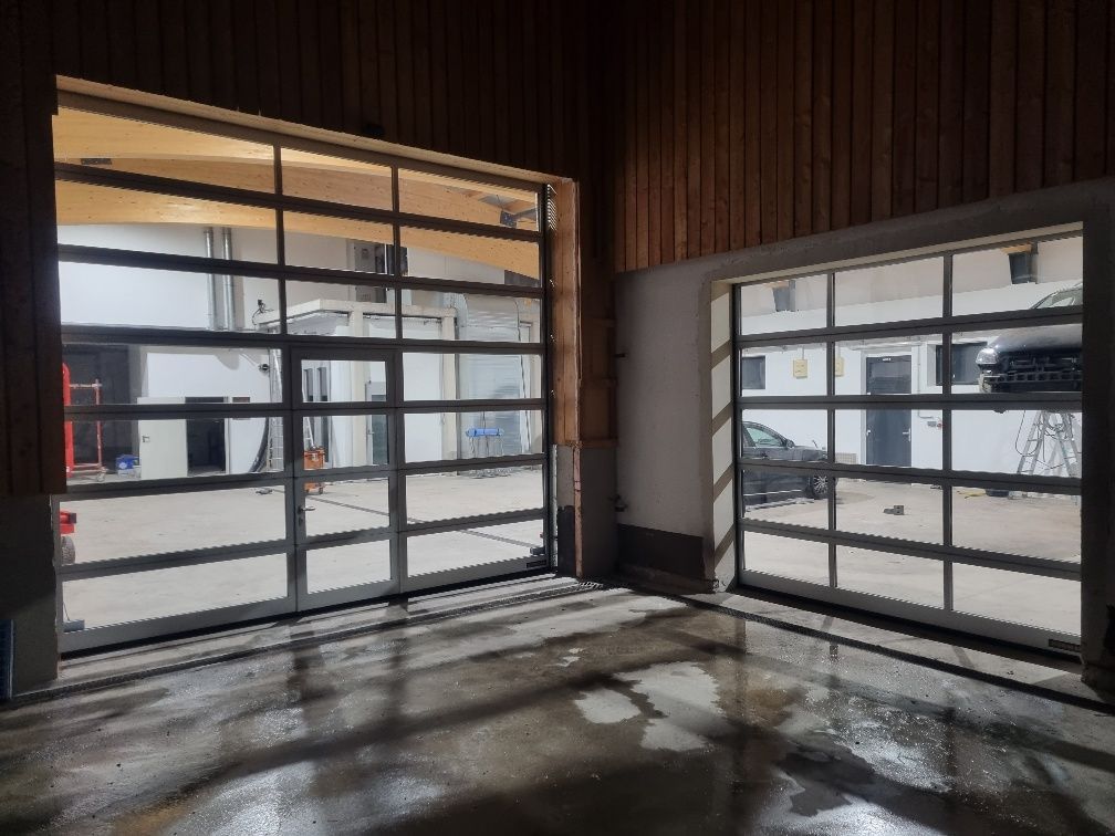 Eine Garage mit vielen Fenstern und einem im Hintergrund geparkten Auto.