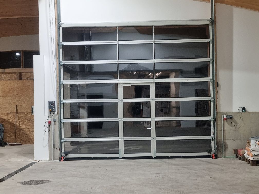 In einem Gebäude ist ein großes Glasgaragentor geöffnet.