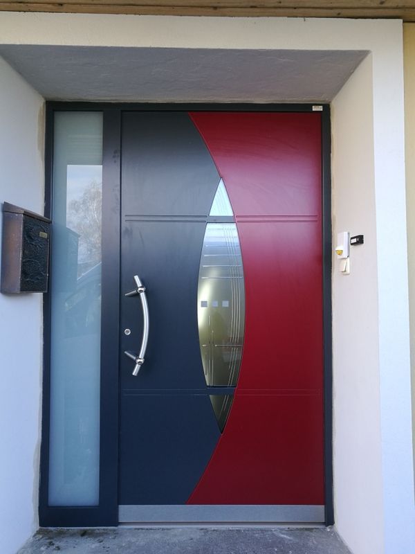 Eine rot-schwarze Tür mit einem Briefkasten davor