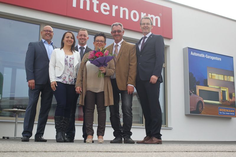 Eine Gruppe von Menschen steht vor einem Gebäude mit der Aufschrift „Internorm“