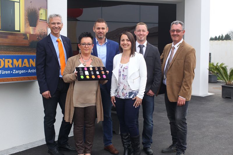 Eine Gruppe von Menschen steht vor einem Schild mit der Aufschrift „Norman“