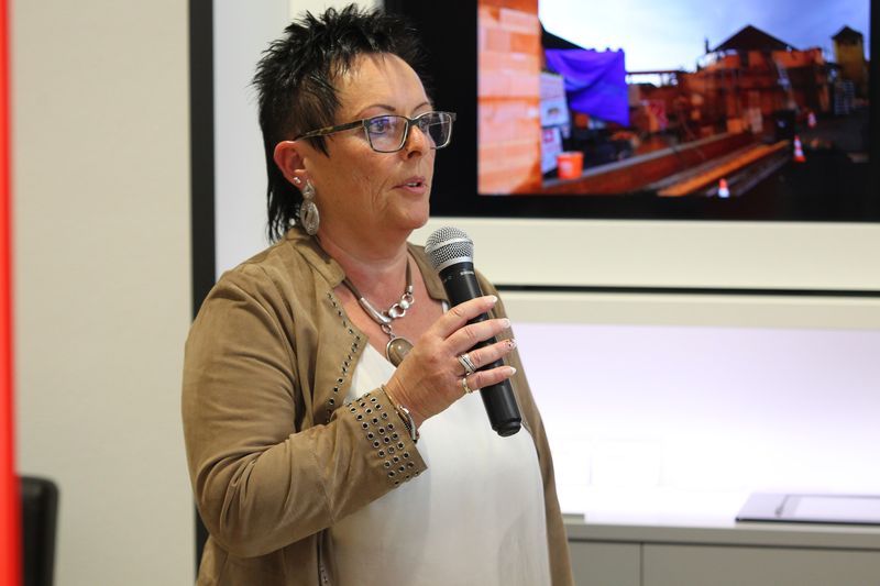 Eine Frau hält ein Mikrofon vor einem Bildschirm.