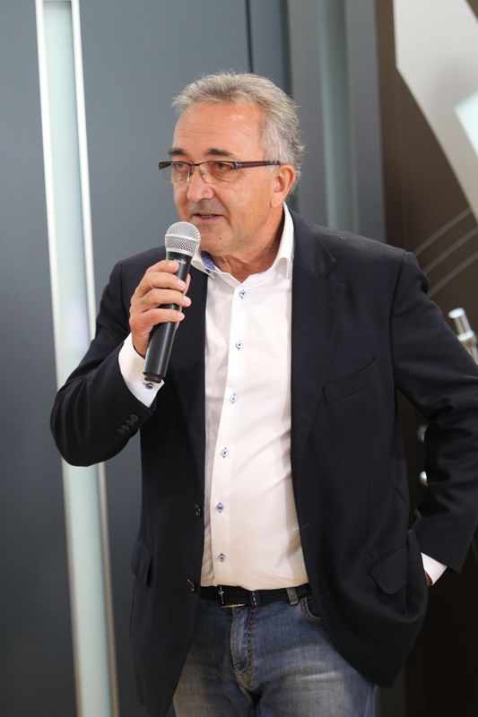 Ein Mann im Anzug hält ein Mikrofon in der Hand.