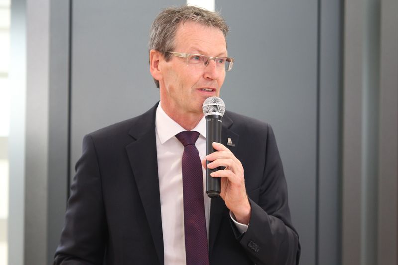 Ein Mann in Anzug und Krawatte hält ein Mikrofon.