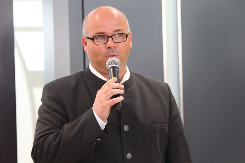 Ein Mann im Anzug hält ein Mikrofon in der Hand.