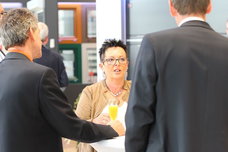 Ein Mann im Anzug spricht mit einer Frau , die ein Glas Orangensaft hält.