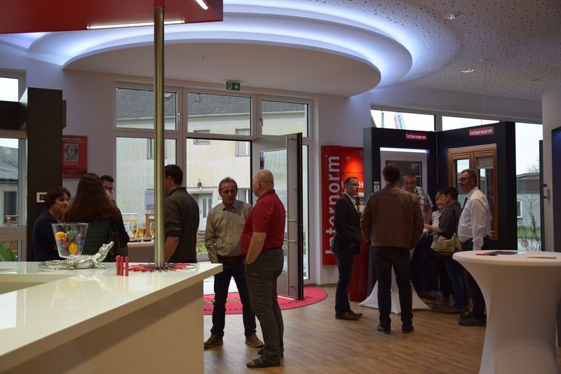 Eine Gruppe von Menschen steht in einem Raum mit einem Schild mit der Aufschrift „Internorm“