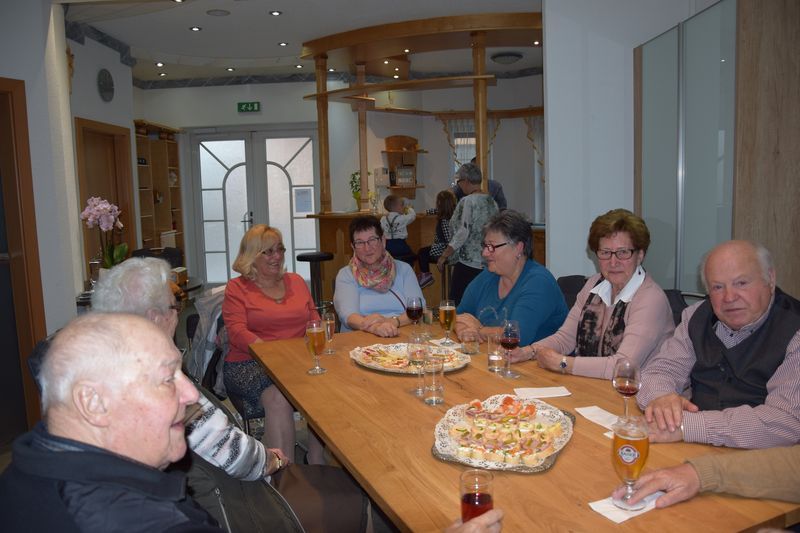 Eine Gruppe Leute sitzt um einen Tisch herum, isst Pizza und trinkt Bier.
