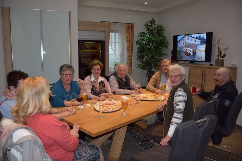 Eine Gruppe Leute sitzt um einen Tisch und isst Pizza.