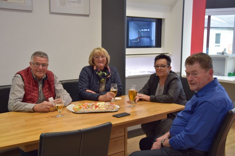 Eine Gruppe Leute sitzt um einen Tisch herum, isst Pizza und trinkt Bier.