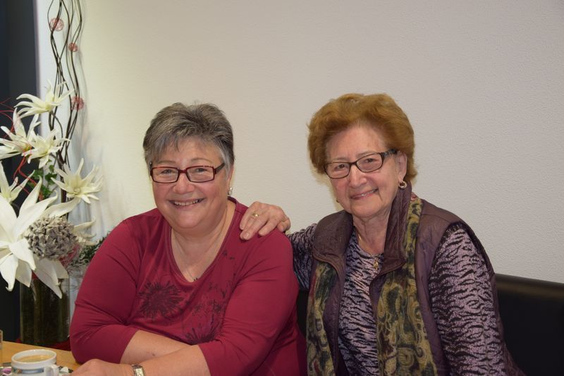 Zwei Frauen posieren zusammen für ein Foto, während sie an einem Tisch sitzen.