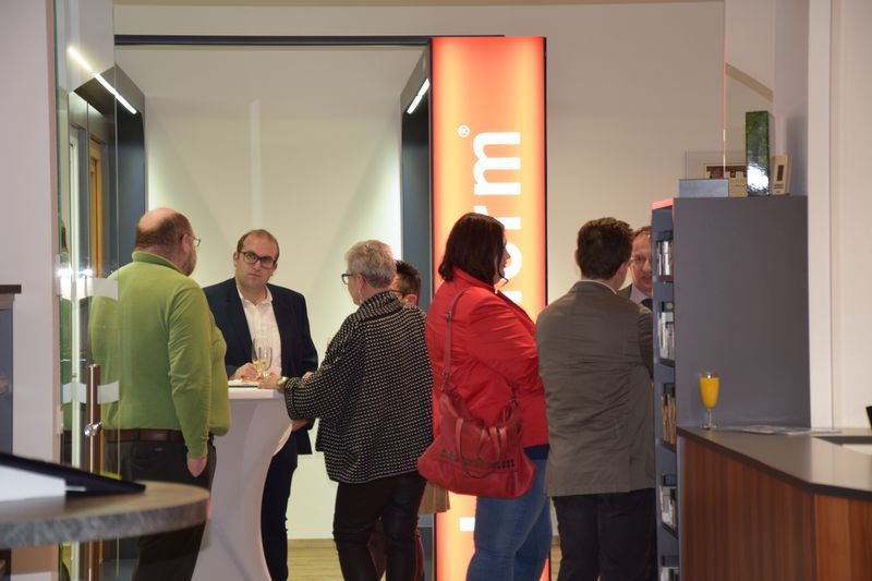 Eine Gruppe von Leuten steht um einen Tisch herum vor einem Schild mit der Aufschrift „U“.