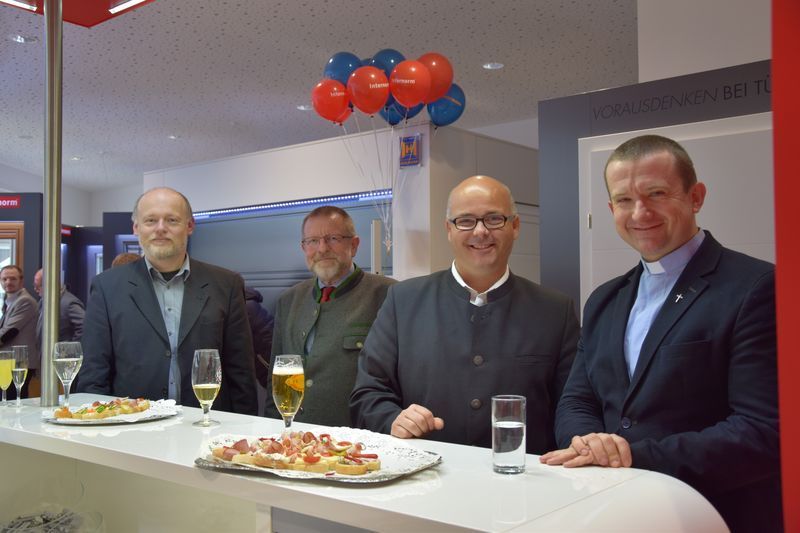 Eine Gruppe von Männern sitzt mit Tellern voller Essen und Gläsern voller Bier an einem Tisch.