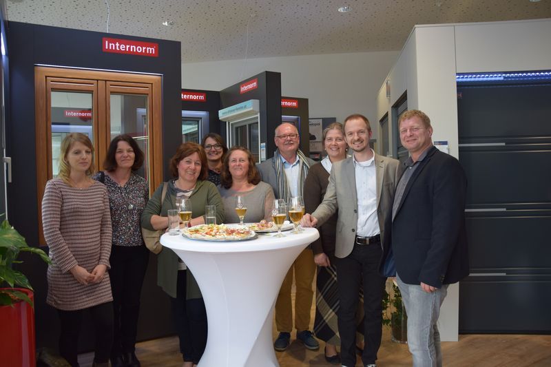 Eine Gruppe von Leuten steht in einem Raum um einen Tisch herum.