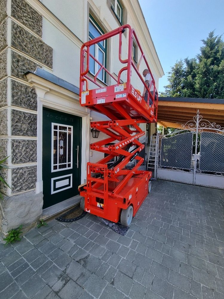 Eine rote Scherenbühne steht vor einem Gebäude