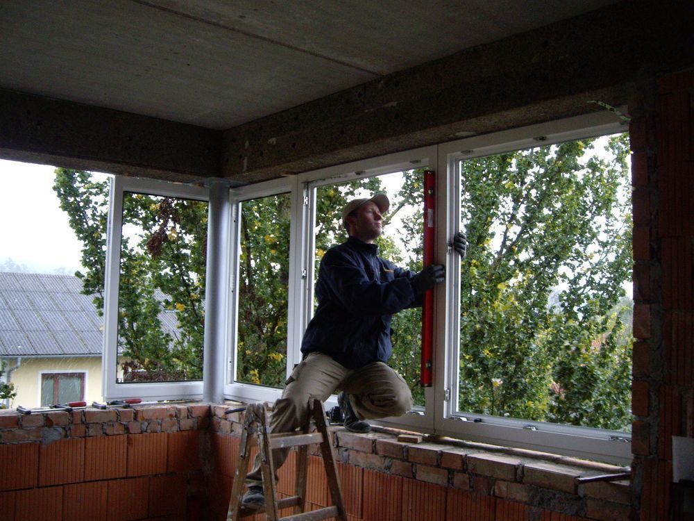 Ein Mann misst ein Fenster mit einer roten Wasserwaage