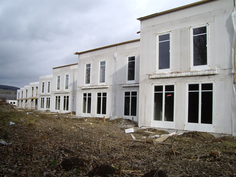 Auf einem Feld wird eine Reihe weißer Häuser gebaut