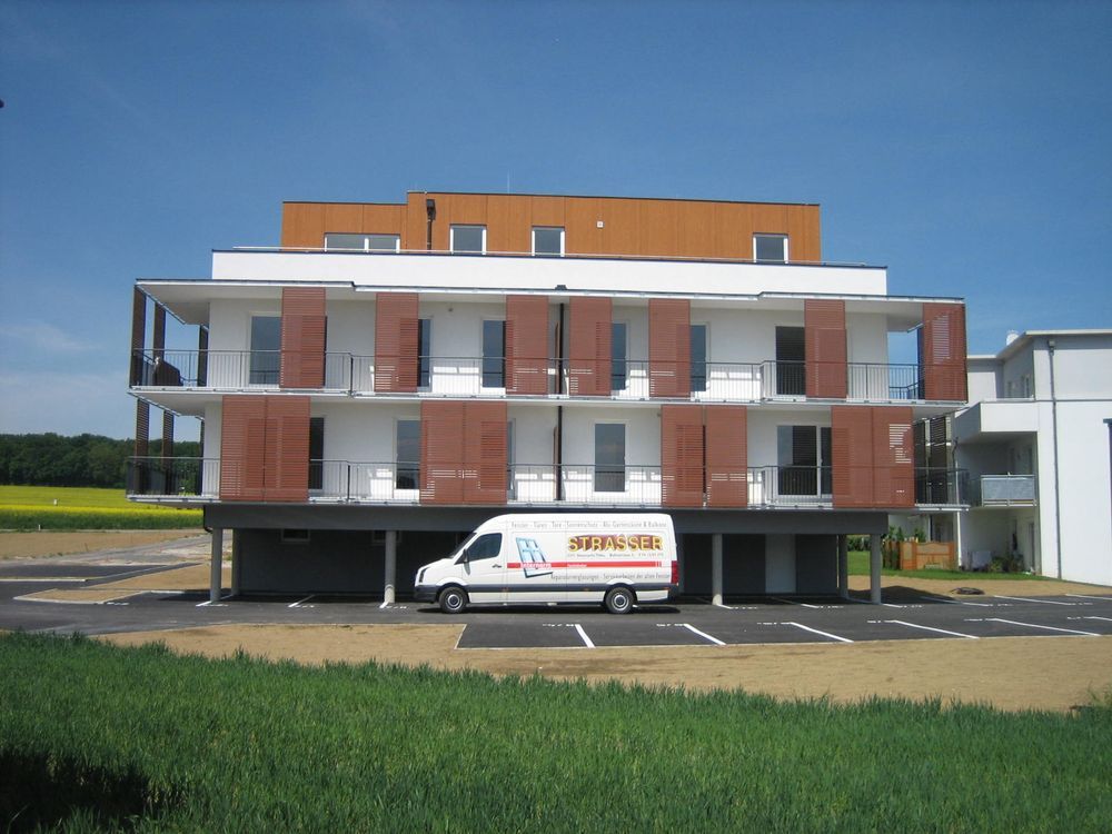 Ein weißer Lieferwagen steht vor einem großen Gebäude