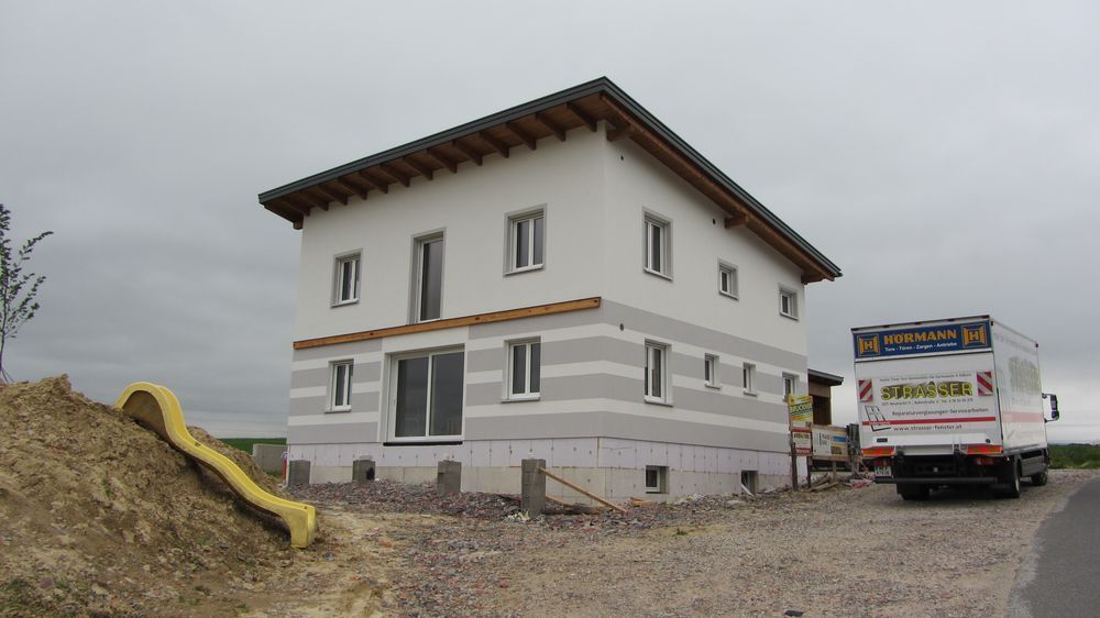 Es wird ein weißes Haus gebaut, davor parkt ein Lastwagen.