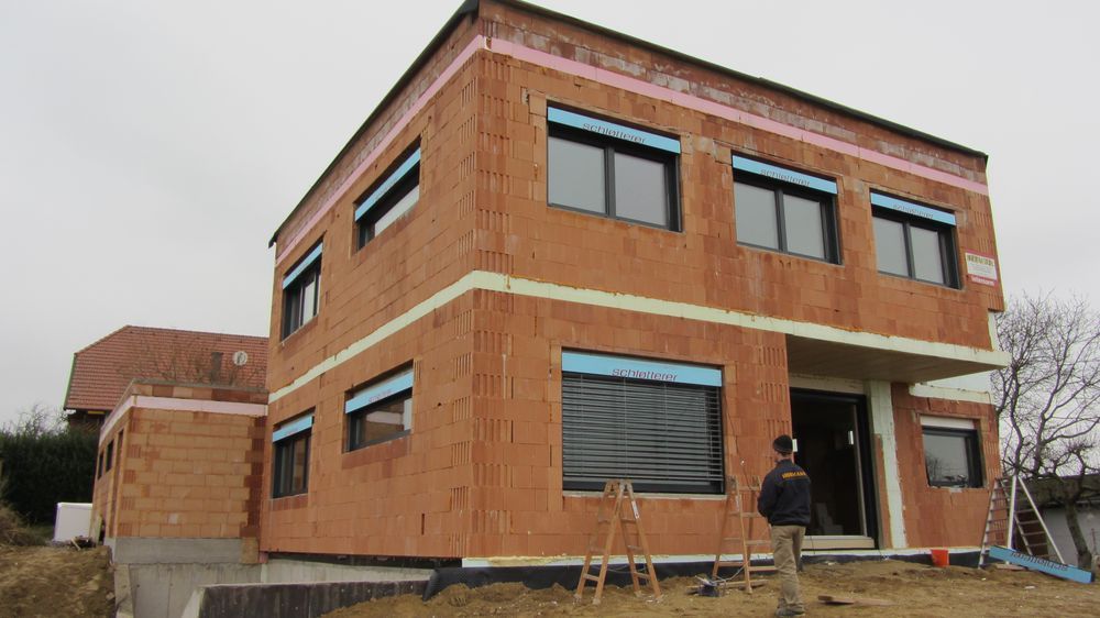 Ein Mann steht vor einem im Bau befindlichen Backsteingebäude.