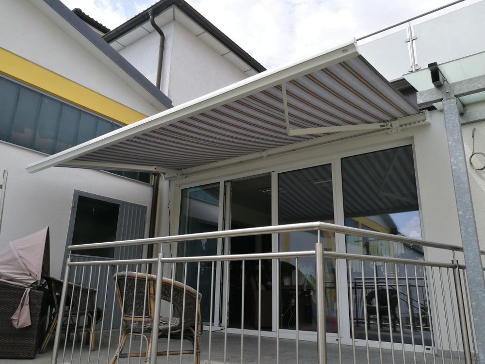 Ein Balkon mit gestreifter Markise und Edelstahlgeländer